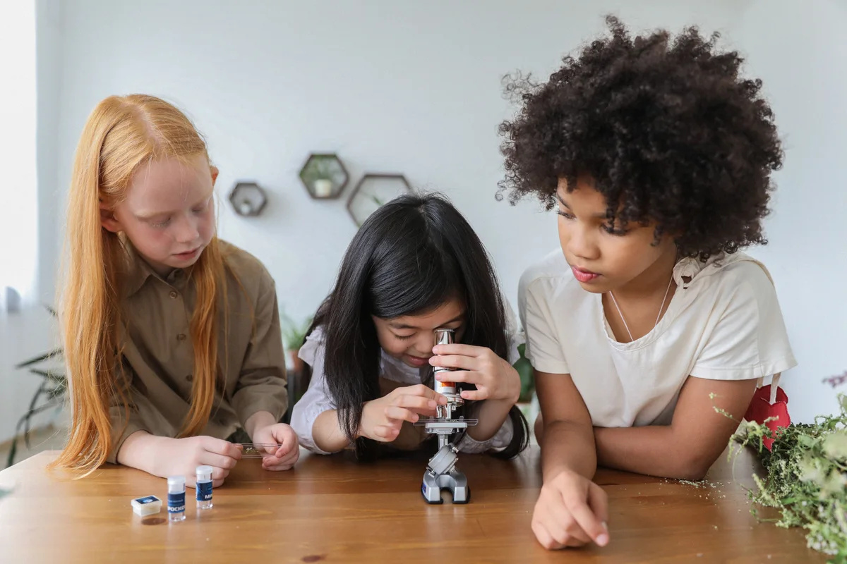 Niñas explorando con un microscopio en una actividad de ciencia